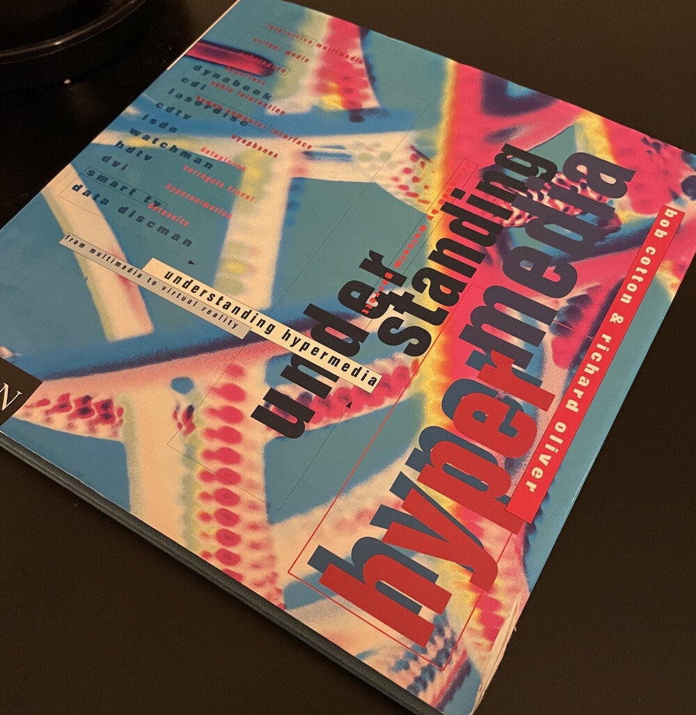 A square coffee-table book, with a chaotic 90s design in pink and cyan.